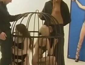 Muscular guys humiliate two cute young chicks and fuck them in a cage